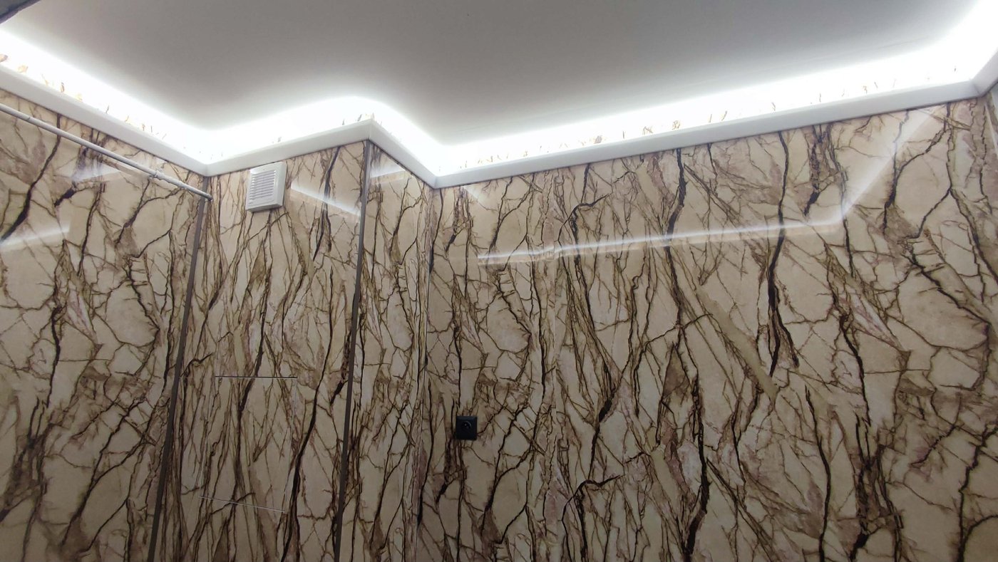 Koupelna s mramorovými obklady a LED osvětlením po obvodu stropu